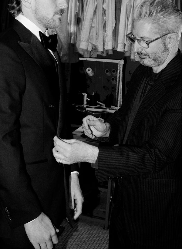 A tailor is shown making adjustments to a tuxedo.