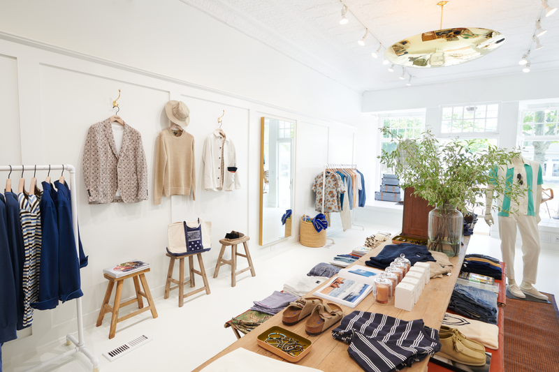The East Hamptons bright and airy store is shown, with summer clothing hanging and folded, and beautiful store accents shown.  