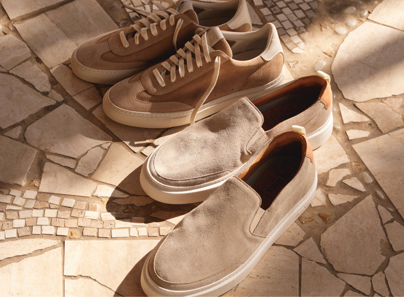 Different styles and colors of leather and suede sneakers are shown.