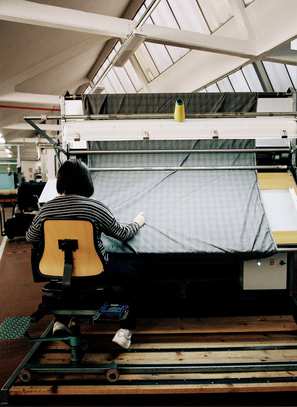 A worker is shown weaving fabric at a large machine.